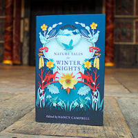 Book titled 'Nature Tales for Winter Nights' by Nancy Campbell on a wooden surface with a blurred background.