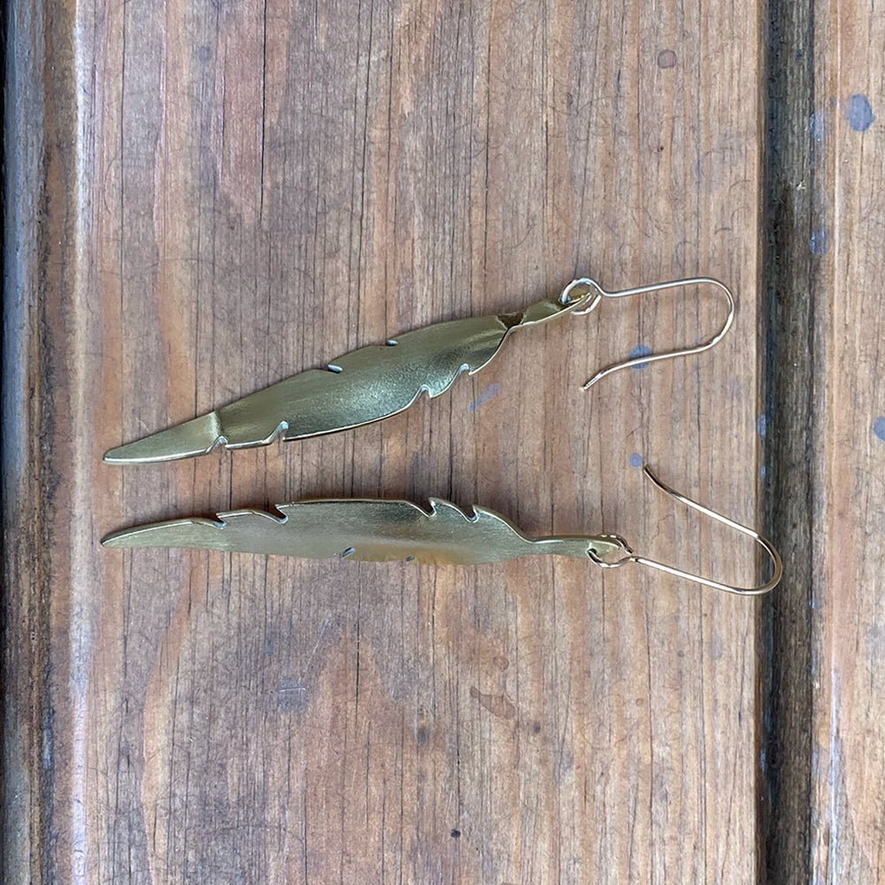 
                      
                        brass metal quill shaped earrings with gold coloured findings.
                      
                    