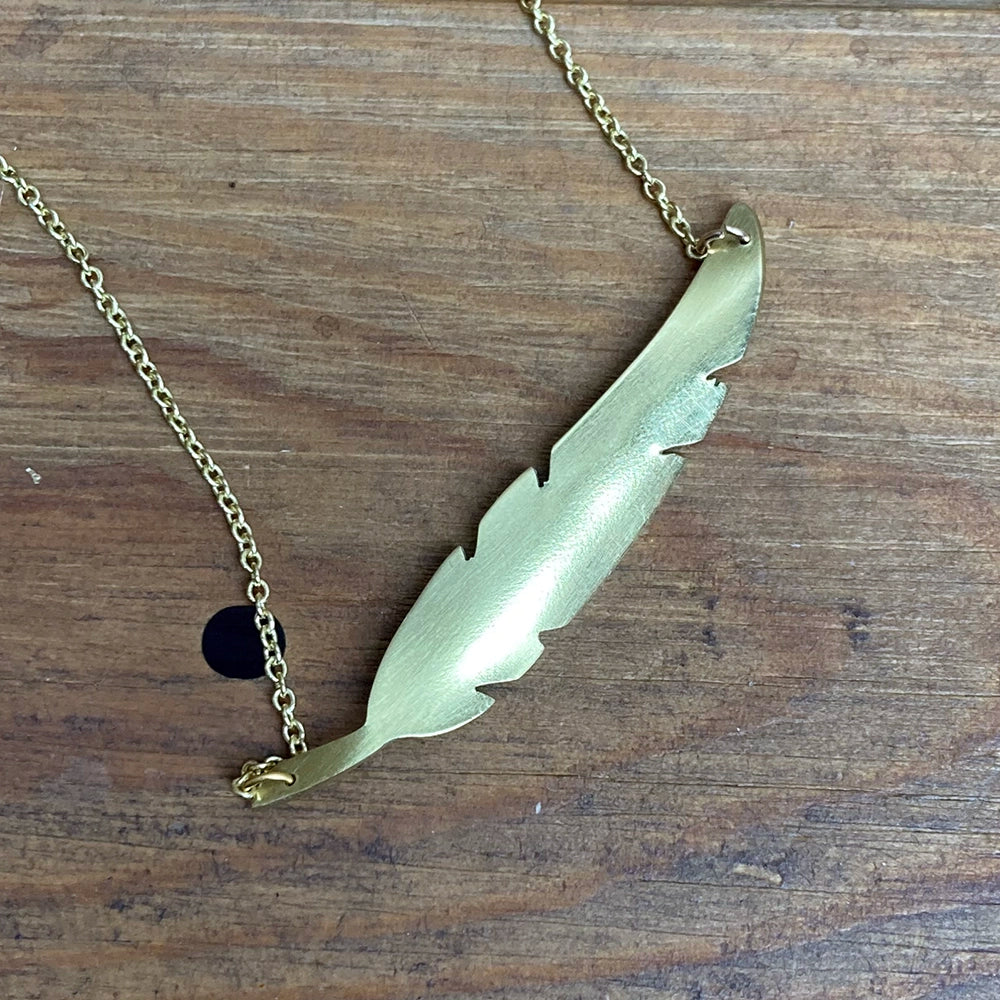 
                      
                        brass metal quill shaped necklace with a gold coloured chain
                      
                    