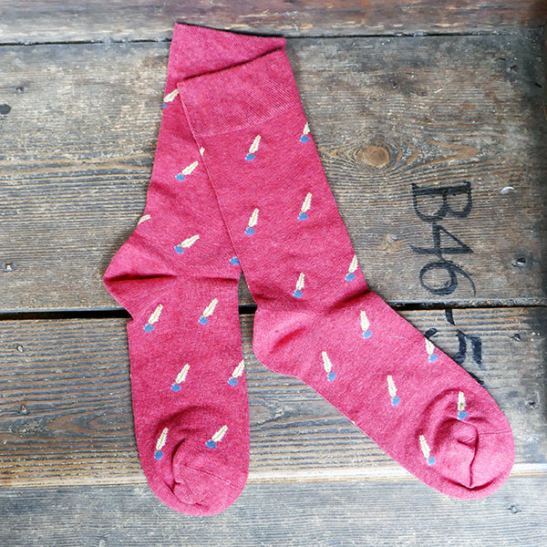 Red socks with a repeating pattern of a quill pen in an ink pot.