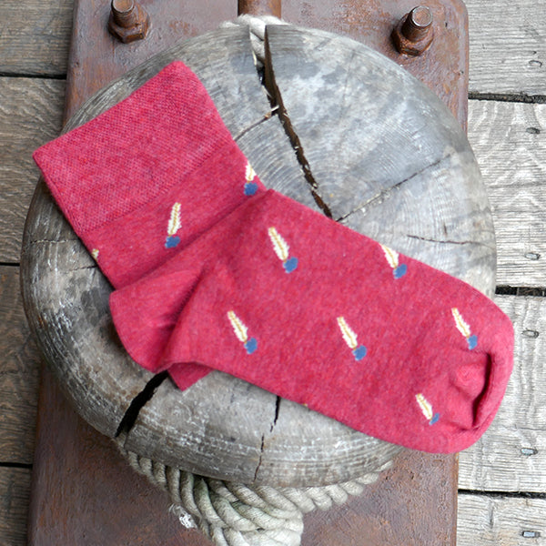 Red socks with a repeating pattern of a quill pen in an ink pot.