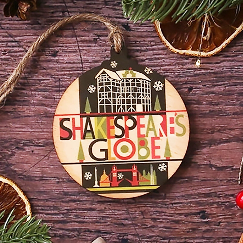 Round wooden decoration with a natural string hanger. The decoration is printed with a black and white image of the Globe Theatre with colourful lettering underneath which reads 'Shakespeare's Globe' on wooden background with Christmas greenery