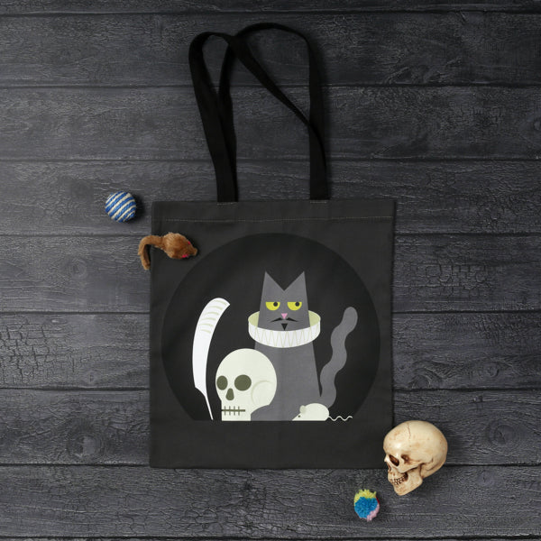 Grey tote bag with black handles, featuring a graphic of a cat in a ruff, holding a quill and with a skull and mouse