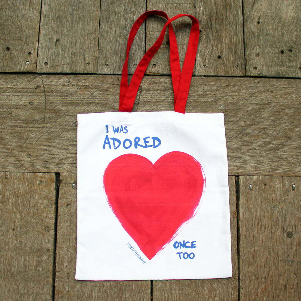 white bag with red handles, printed with a bright red heart and a blue quote