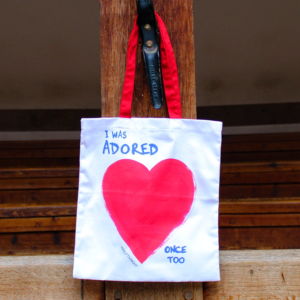 white bag with red handles, printed with a bright red heart and a blue quote