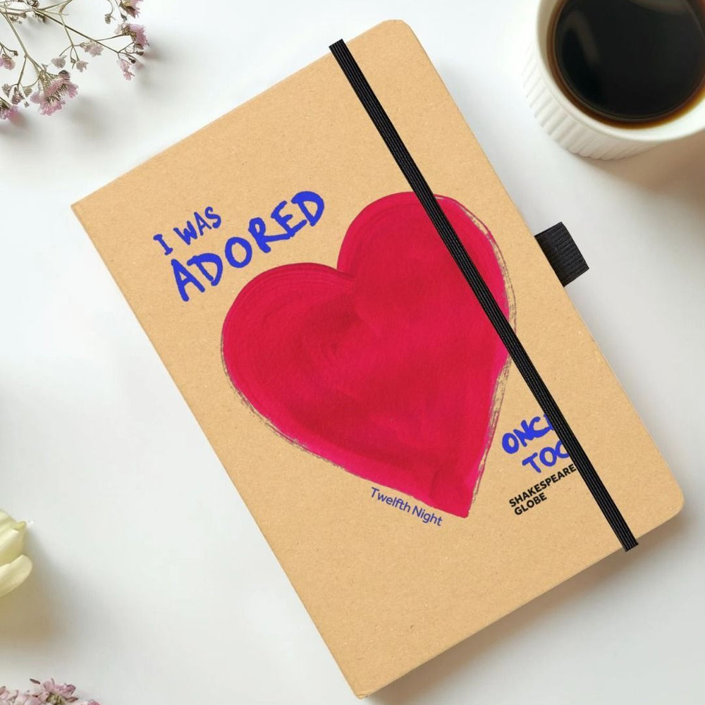 Kraft notebook with red painted heart and blue text and black elastic closure on the side