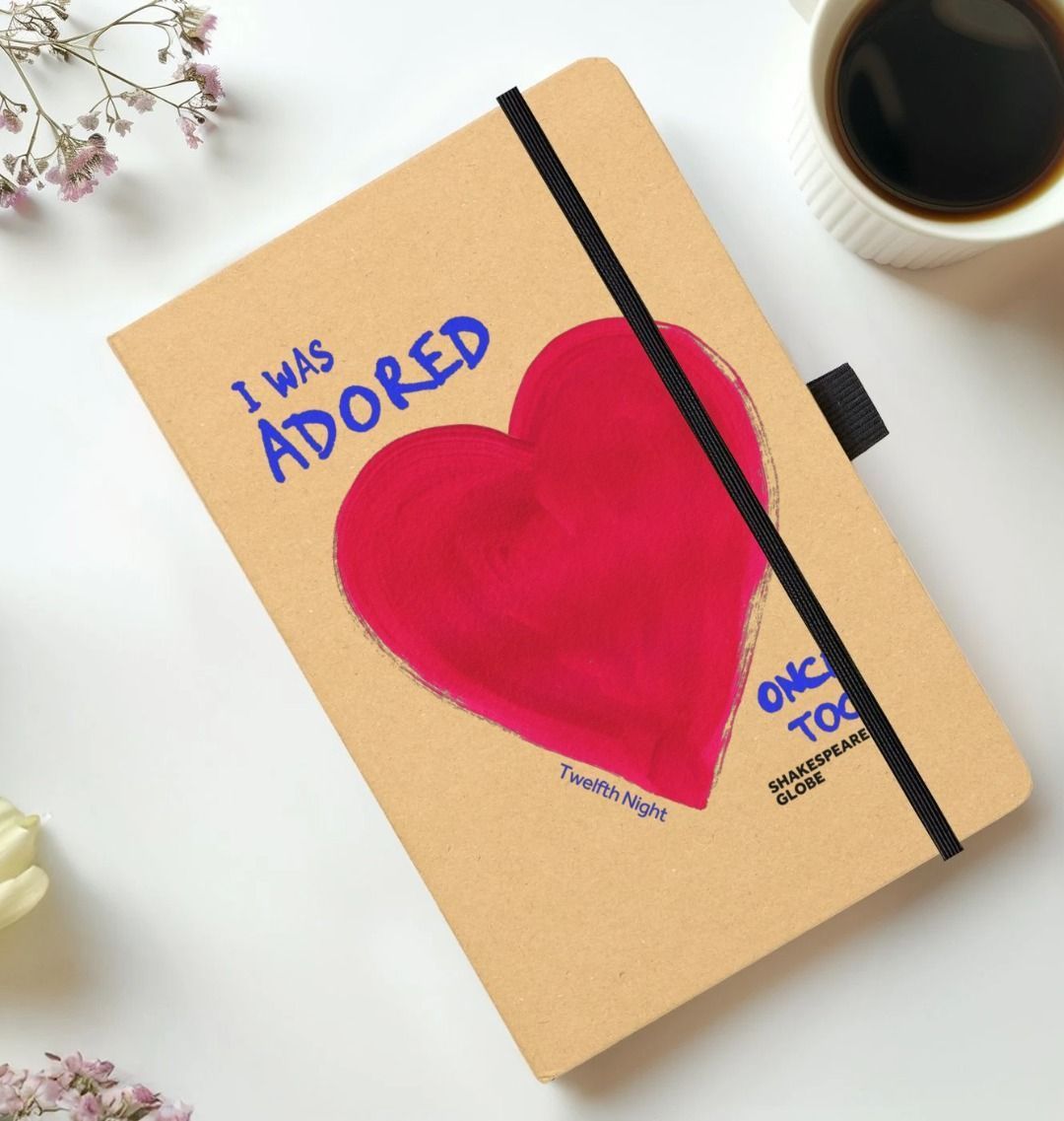 Kraft notebook with red painted heart and blue text and black elastic closure on the side