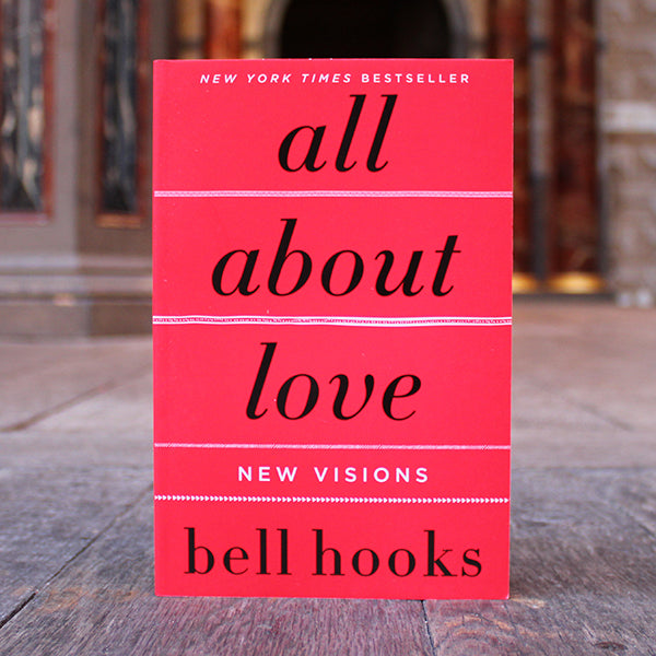 Book titled 'all about love: New Visions' by bell hooks on a wooden surface with a blurred background