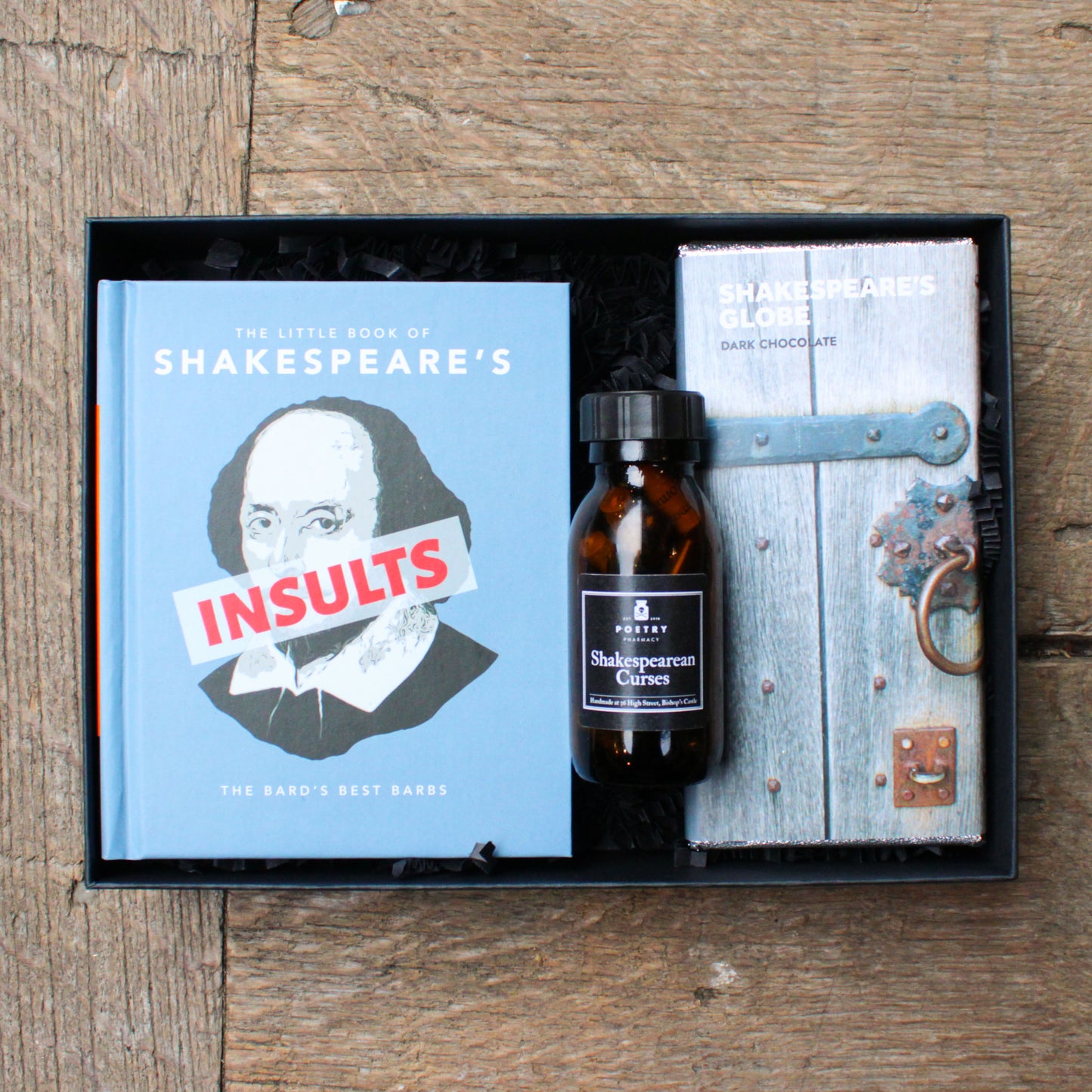 Shakespeare-themed gift set with books and a bottle on a wooden surface