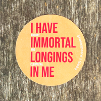 Round yellow sticker with red text on a wooden background