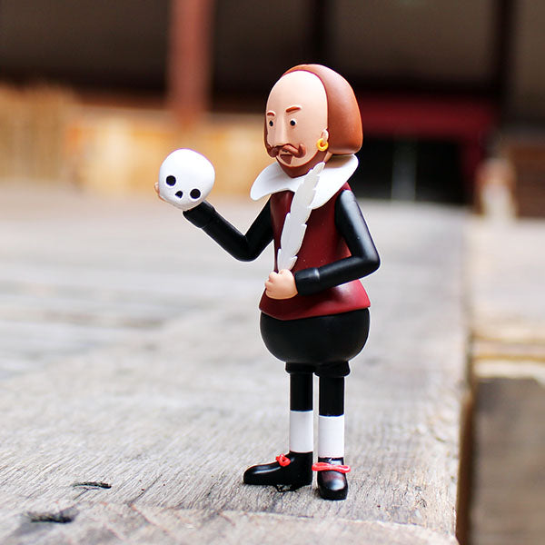 plastic figure of Shakespeare wearing a black and deep red costume holding a white skull and feather