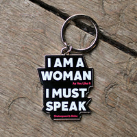 Keychain with text 'I AM A WOMAN As You Like It I MUST SPEAK Shakespeare's Globe' on a wooden surface