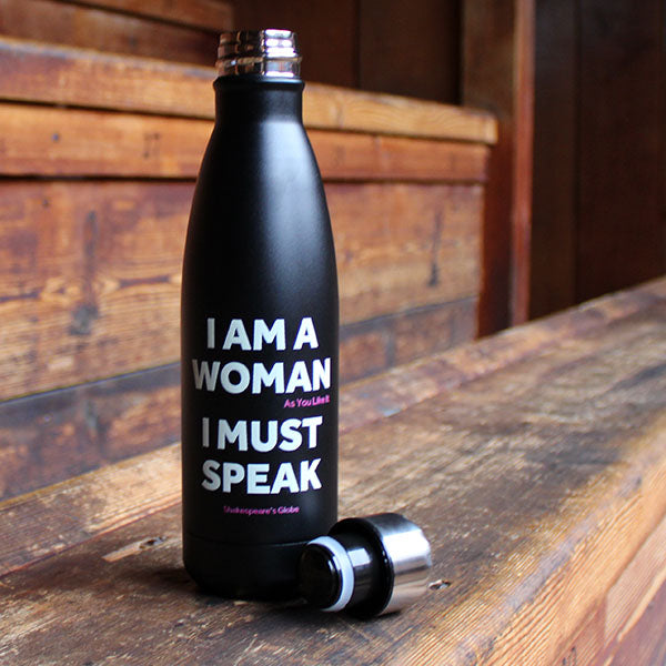 black metal water bottle with a silver cap and white text print standing on a wooden bench