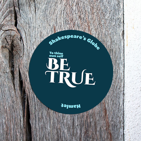 round blue sticker with a 'be true' quote on a wooden wall