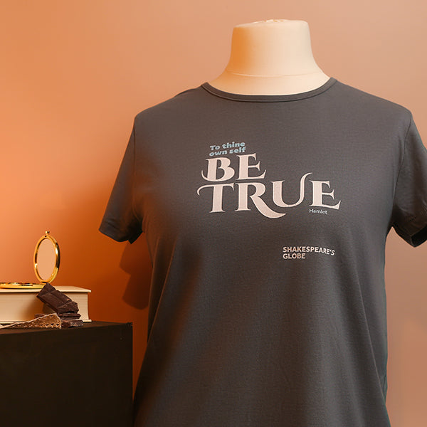 Gray t-shirt with 'BE TRUE' text on a mannequin against an orange background