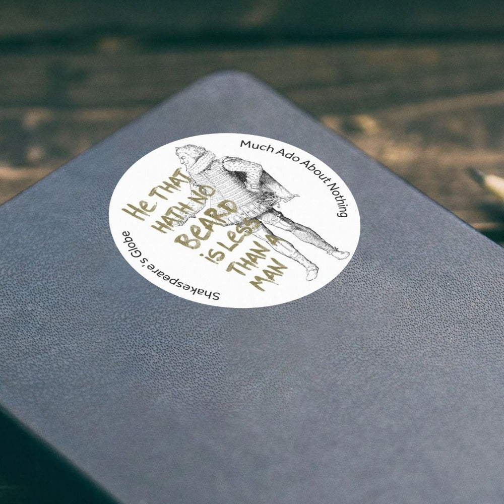 white circular sticker printed with a line drawing of a Tudor gentleman alongside a green quote, stuck on a black leather notebook