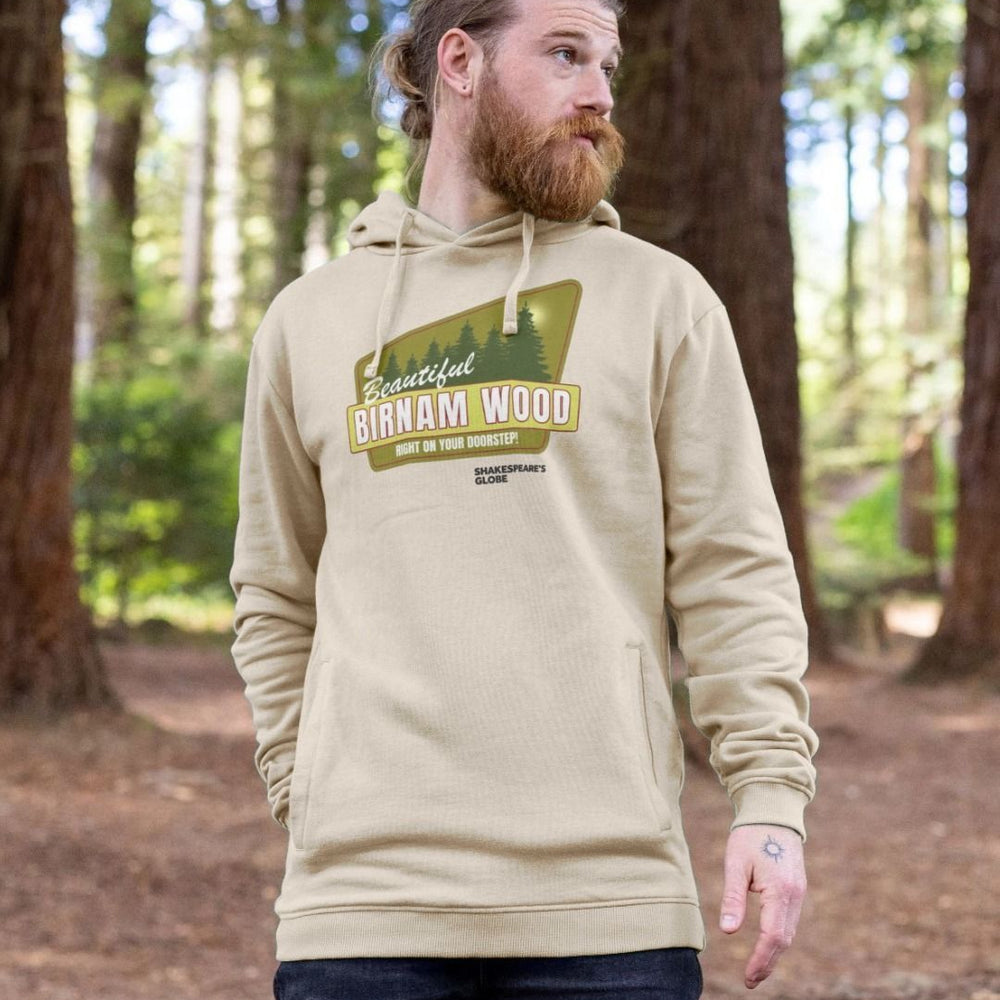 Beige hoodie with yellow and green vintage travel poster image of forest, with white graphic text over top