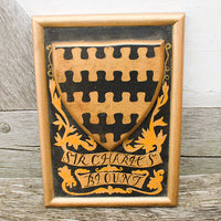 Wooden plaque with a shield design and painted text on a wooden surface