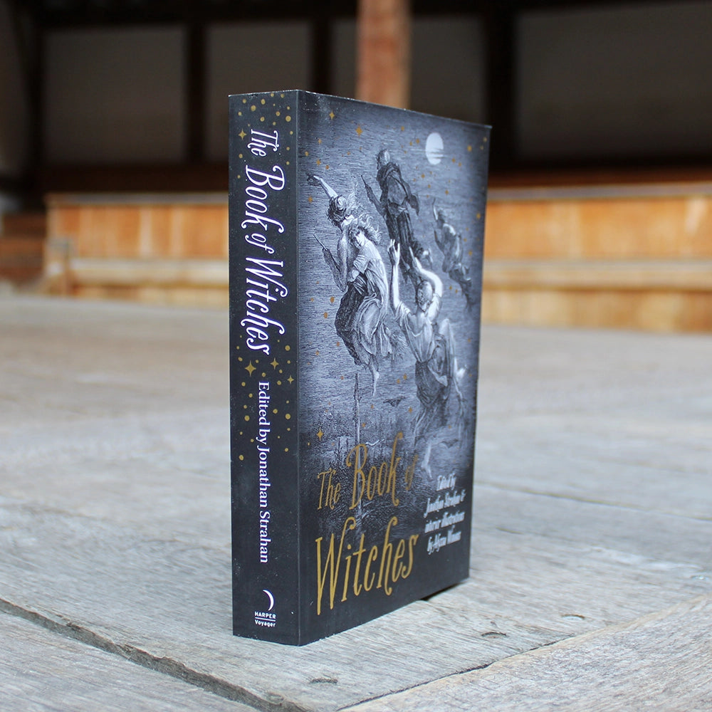 
                      
                        Black paperback book with gold and white text, with witches on broomstick, book at an angle
                      
                    