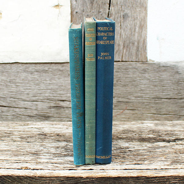 Three vintage books stacked on a wooden surface with a rustic background