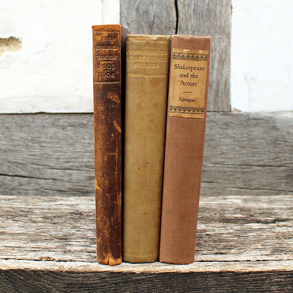 Three old books stacked on a wooden surface with a rustic background