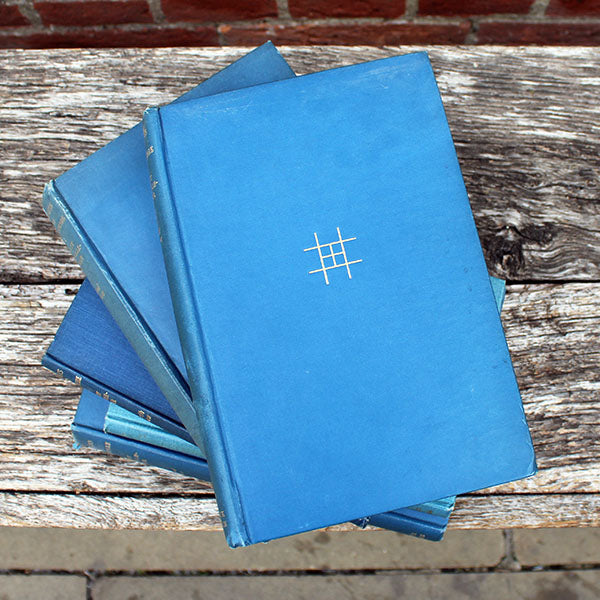 Stack of blue notebooks with a gold symbol on a wooden surface