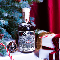 A bottle of Hive Mind cherry mead, featuring a detailed black and white illustration label of Shakespeare's Globe Theatre, surrounded by Christmas greenery