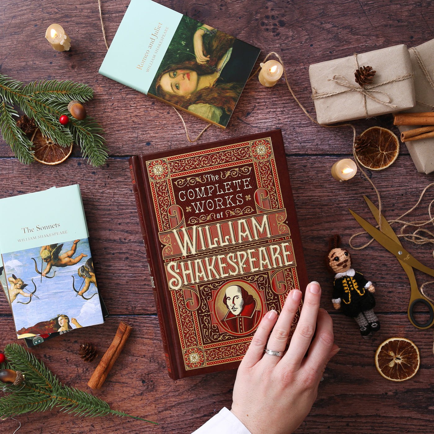 Hardback Shakespeare play texts lying on wood plank floor, with scissors, string, and wrapped brown packages