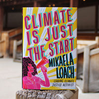 Book titled 'Climate is Just the Start' by Mikaela Loach on a wooden surface with a blurred indoor background.