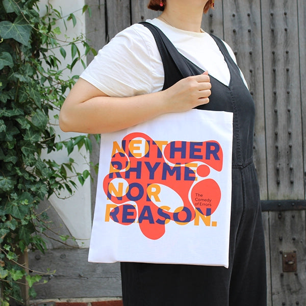 
                      
                        White cotton tote bag with 2 black handles, with orange bubbly graphic and purple and yellow text
                      
                    