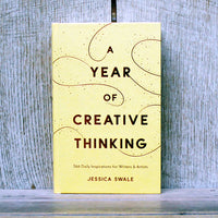 Book titled 'A Year of Creative Thinking' by Jessica Swale on a wooden surface with a wooden background.