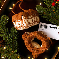 Two crocheted decorations on a Christmas tree with a label reading 'Shakespeare's Globe'.