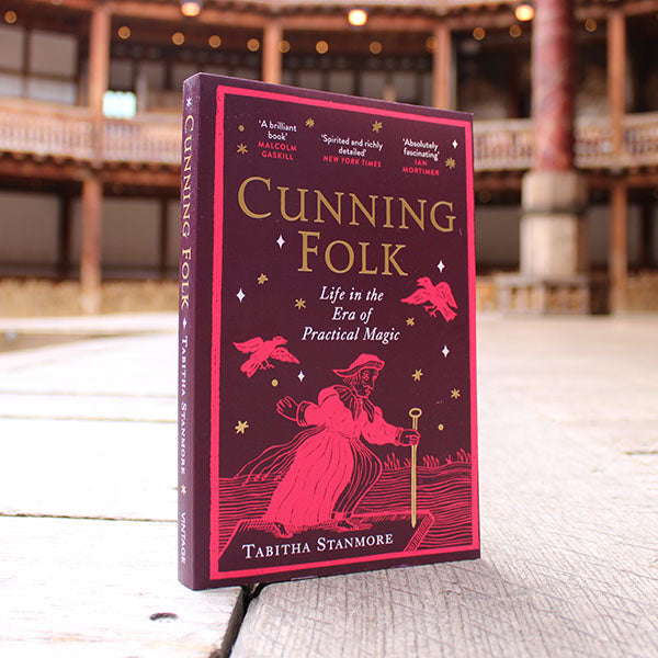 paperback book with a purple and pink cover standing on a wooden surface