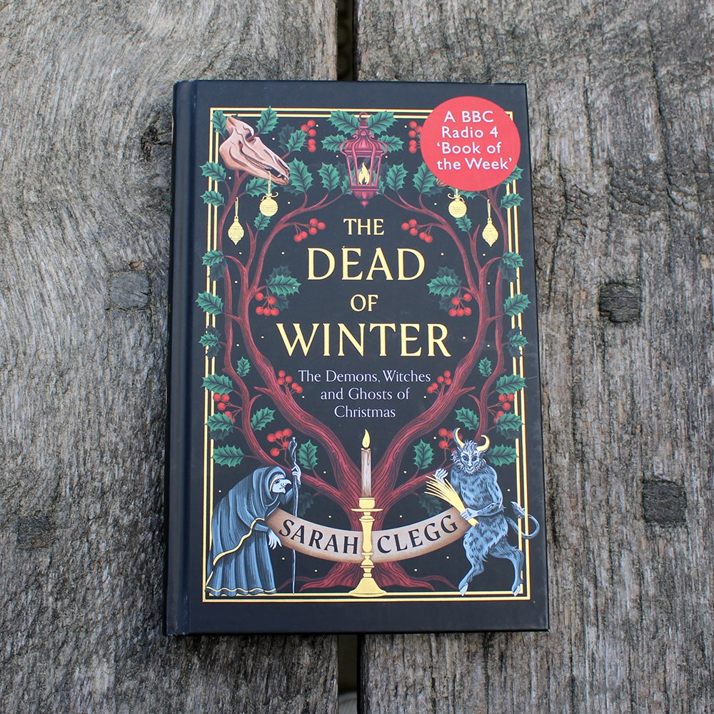 Black hardback book with red, green and gold wintery motif and gold writing