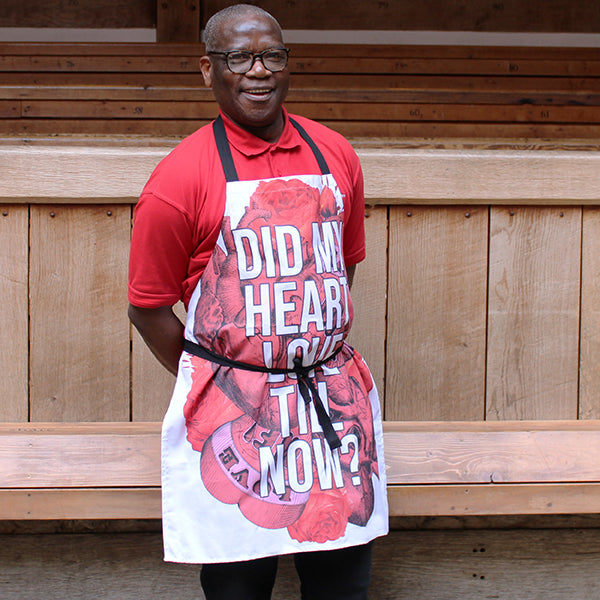 White cotton apron with black ties and red tattoo style graphic hearts with white text overlayed