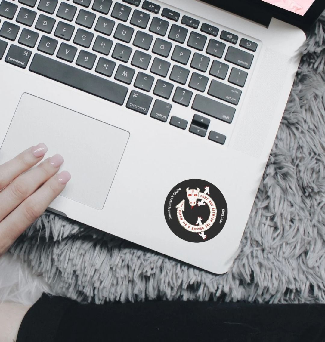 Black circular sticker with white graphic of a dragon, stuck on a silver laptop