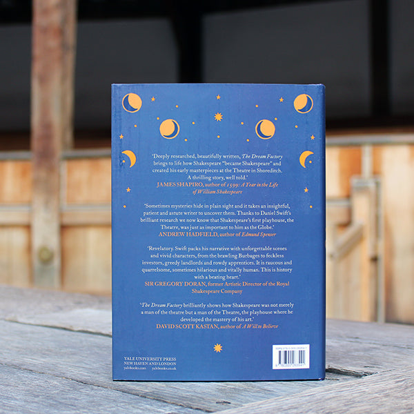 
                  
                    Navy blue hardback book with gold and white writing, sitting on wooden stage, book back
                  
                