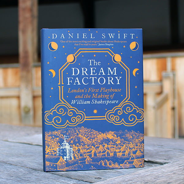 Navy blue hardback book with gold and white etchings and writing, sitting on wooden stage