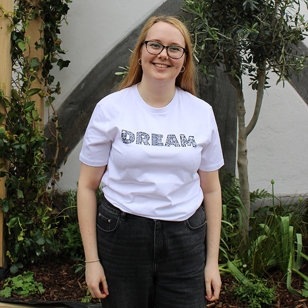 
                  
                    White unisex tshirt with navy blue graphic text across the chest depicting DREAM
                  
                