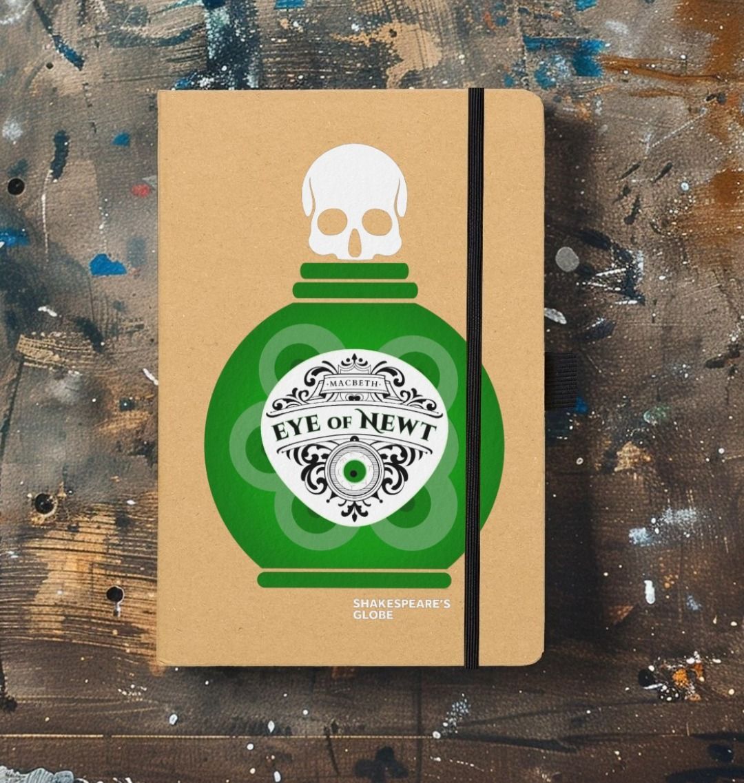 Kraft notebook with graphic depiction of green eye of newt bottle on the front, with black elastic closure on the side