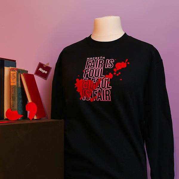 Black sweatshirt on a mannequin with red text reading “Macbeth: Fair is foul & foul is fair” against a purple background.