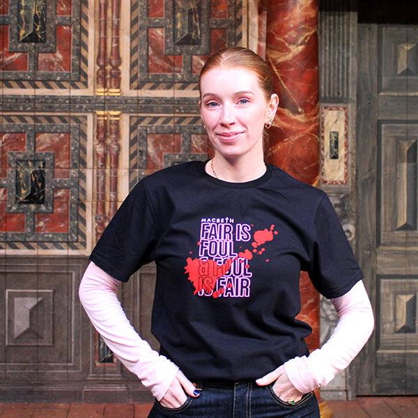 Black cotton t-shirt with hot pink central quote text and blood smear image on female model with red hair tied back