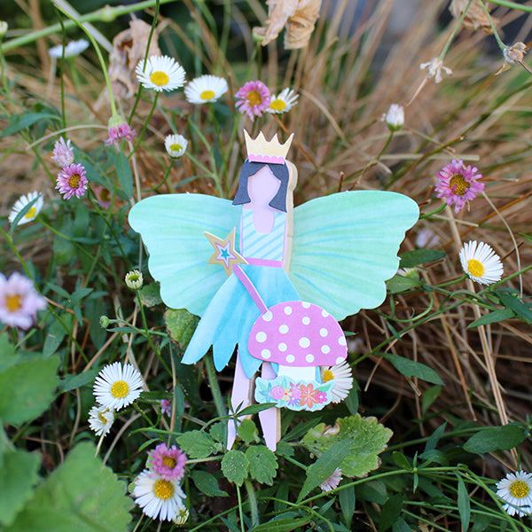 Paper peg fairy with short black hair, gold crown, teal wings and dress, pink and gold wand, and mushroom
