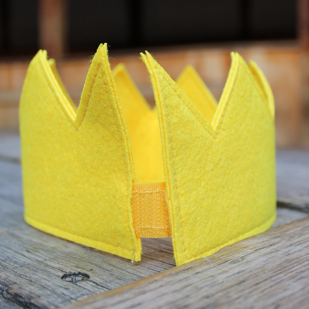 
                  
                    Canary yellow felt crown sitting on wooden stage
                  
                