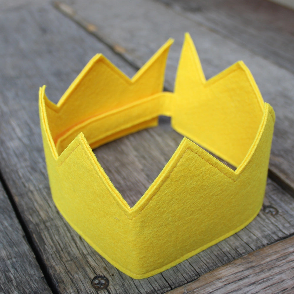 
                  
                    Canary yellow felt crown sitting on wooden stage
                  
                