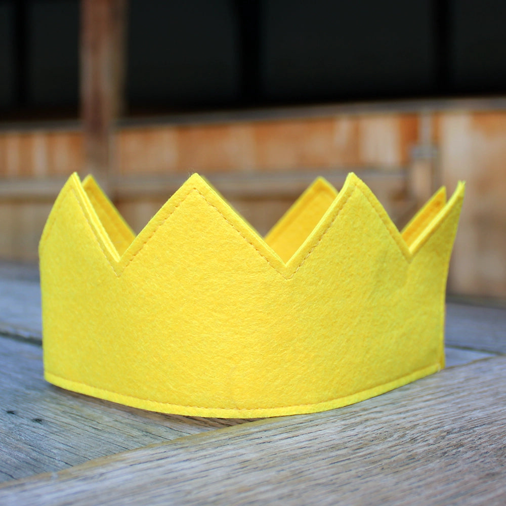 Canary yellow felt crown sitting on wooden stage