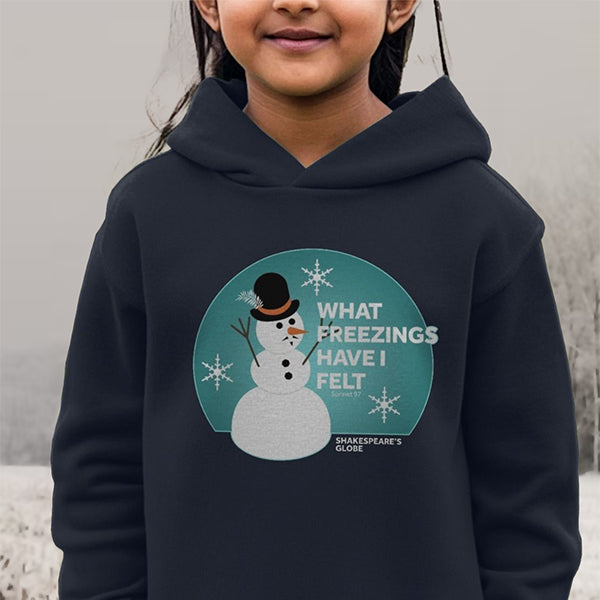 Child wearing a blue hoodie with a snowman graphic and text, standing against a neutral background.