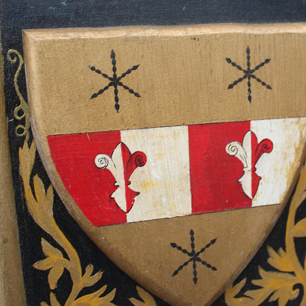 Close-up of a coat of arms with red, white, and gold colors on a brown background.