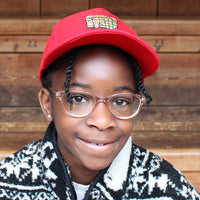 Red cotton baseball cap with curved bill and embroidered cartoon Shakespeare's Globe on front