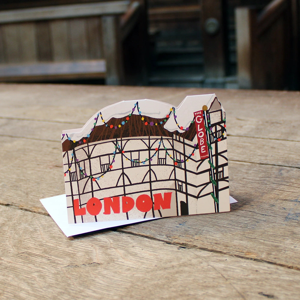 Die cut Christmas card featuring the Globe Theatre adorned with colourful Christmas lights and a snowy thatched roof